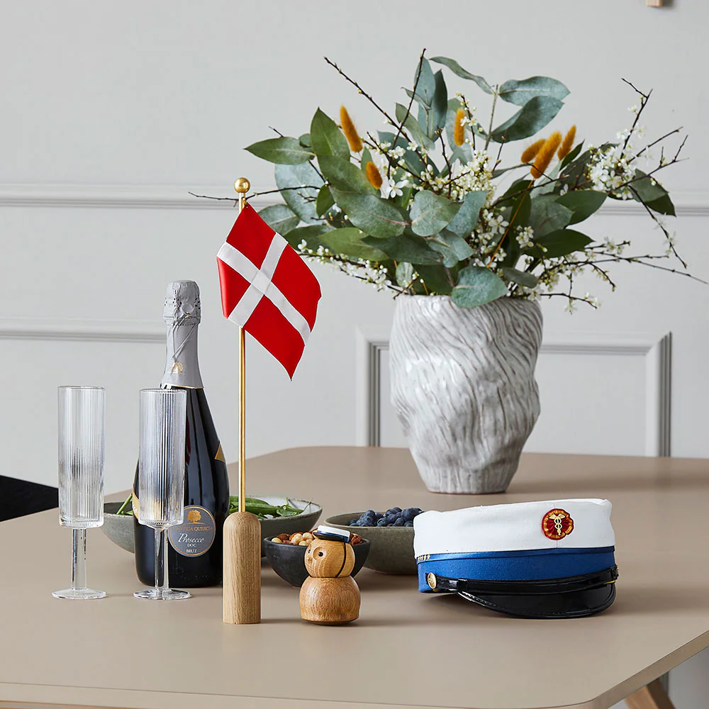 Celebrating bordflag fra Andersen på spisebord med champagne og en blå studenterhue