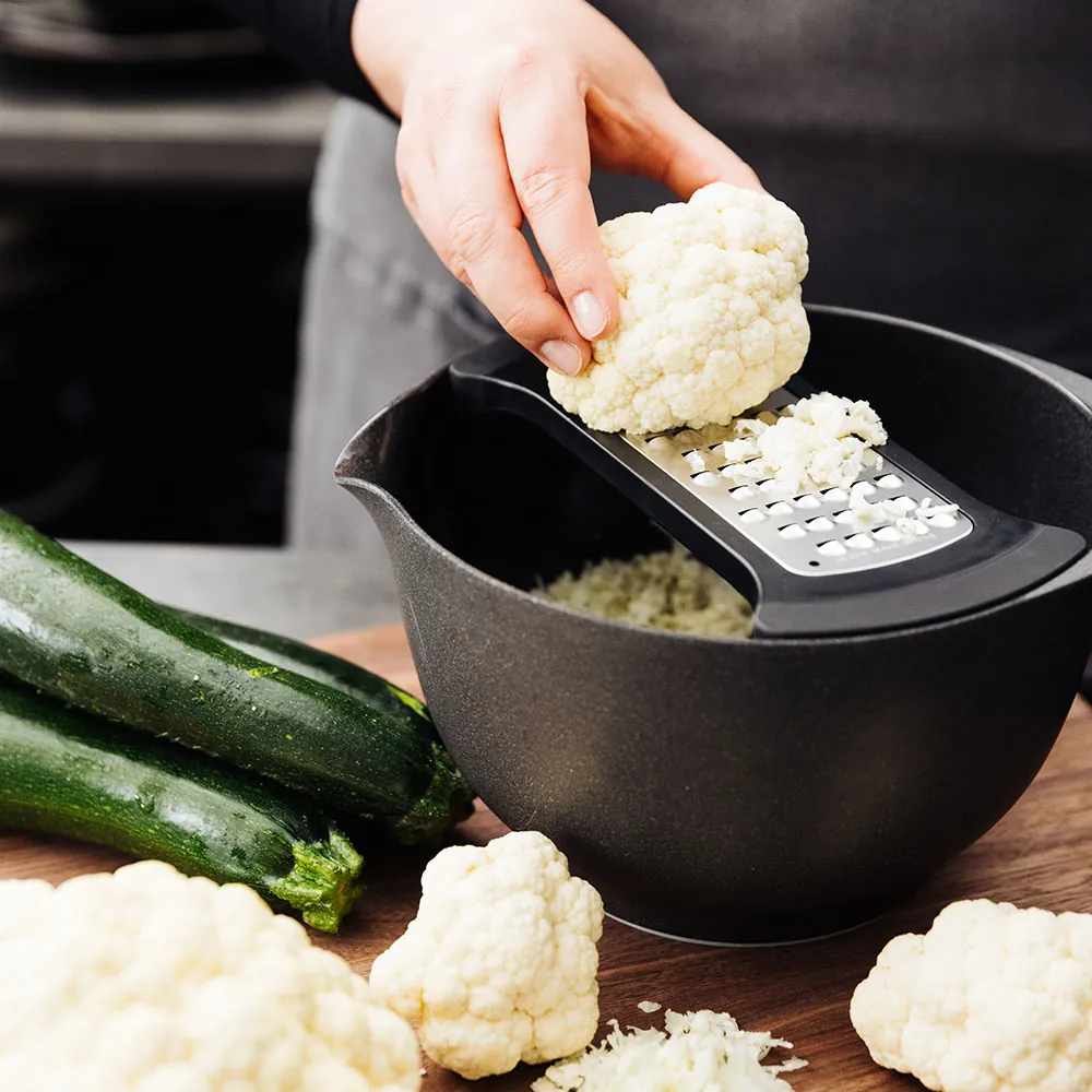 Person anvender Microplane coarse bowl grater til at rive blomkål
