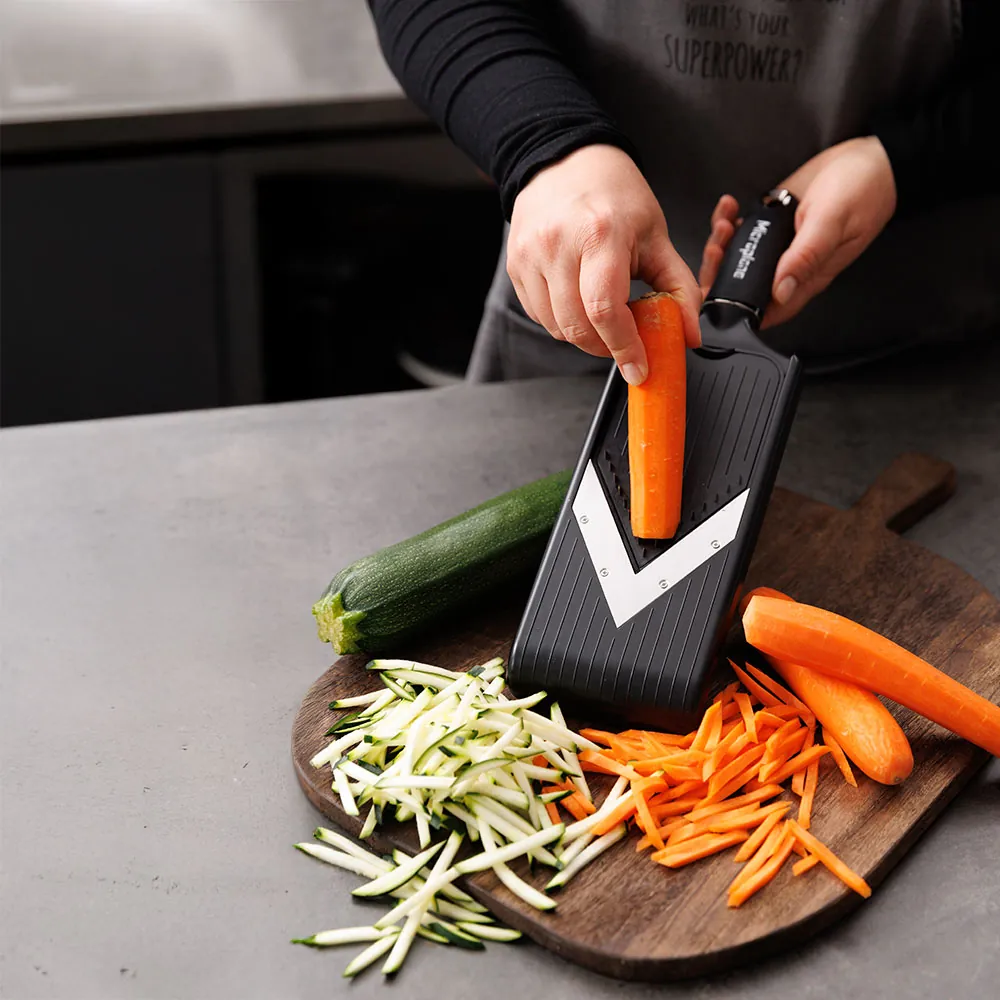 Person anvender Microplane Mandolin V-slicer til at rive gulerødder