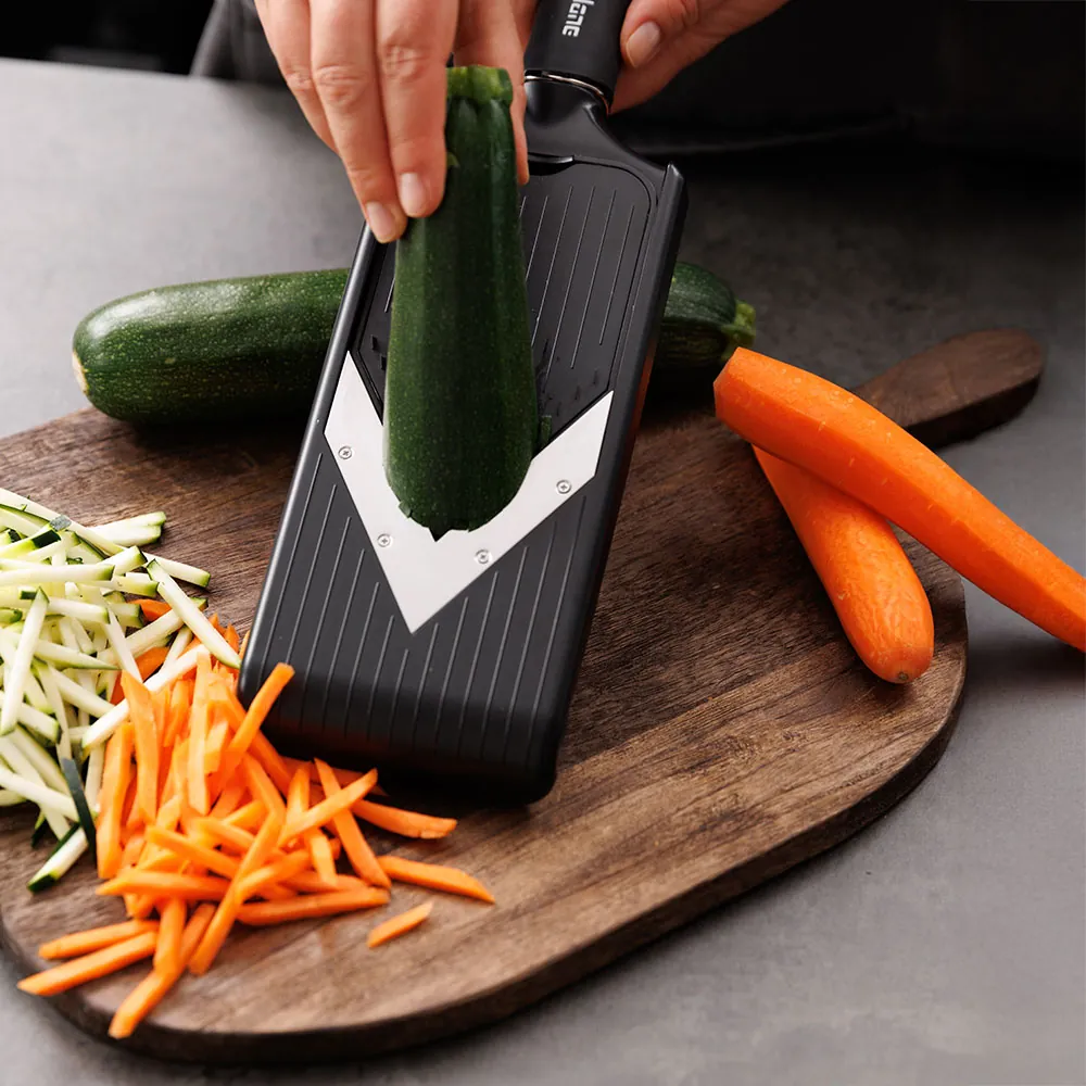 Person anvender Microplane Mandolin V-slicer til at rive squash