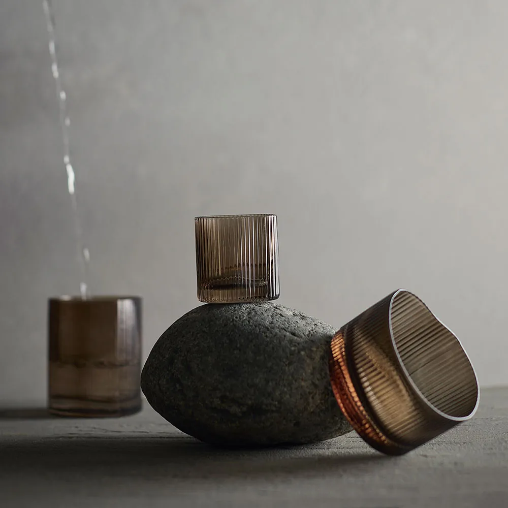 Muubs Ripe glas røget brun balanceret på en sten